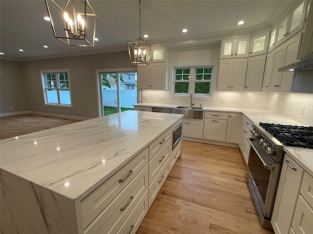 228 Latham Rd, Mineola, NY 11501 - kitchen with a sink, appliances with stainless steel finishes, a chandelier, a center island, and decorative backsplash