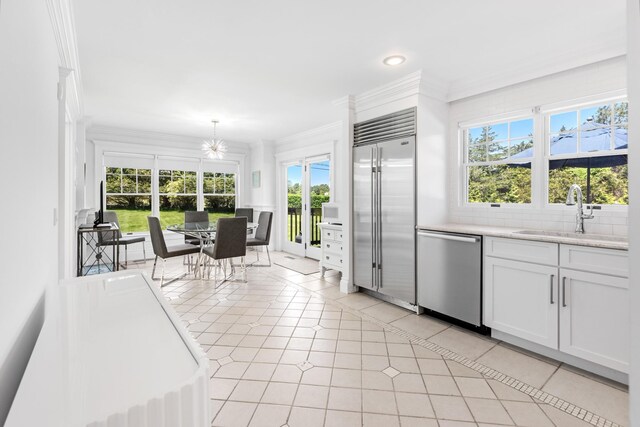 5 Ponds Rd, Water Mill, NY 11976 - kitchen featuring stainless steel appliances, a sink, white cabinets, light tile patterned floors, and crown molding