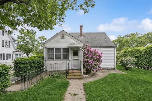 142 Woodhull Ave, Riverhead, NY 11901 - view of front facade featuring a shingled roof, a chimney, entry steps, a front lawn, and a sunroom