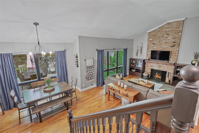 243 Albemarle Rd, White Plains, NY 10605 - living area featuring vaulted ceiling, a chandelier, light wood finished floors, a brick fireplace, and baseboards
