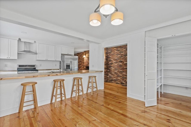 100 Schnackenberg Rd, Call Listing Agent, NY 12075 - kitchen featuring appliances with stainless steel finishes, wall chimney exhaust hood, a kitchen breakfast bar, light wood-style flooring, and ornamental molding