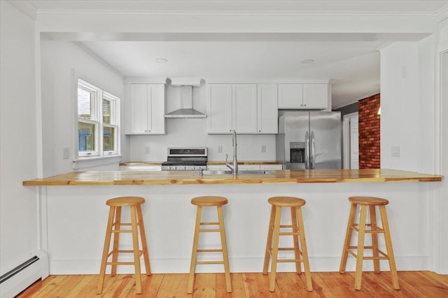 100 Schnackenberg Rd, Call Listing Agent, NY 12075 - kitchen featuring baseboard heating, wall chimney range hood, appliances with stainless steel finishes, a peninsula, and butcher block countertops