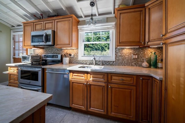 31 Gull Walk, Dunewood, NY 11706 - kitchen featuring appliances with stainless steel finishes, a sink, brown cabinetry, tasteful backsplash, and pendant lighting