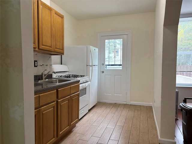 262 Grant Ave, Brooklyn, NY 11208 - kitchen featuring a sink, dark countertops, white range with gas cooktop, brown cabinets, and light wood-style floors