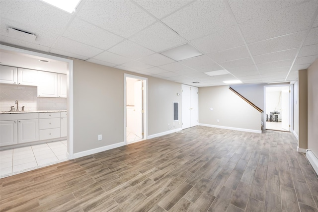 30 Knoll Ln, Glen Head, NY 11545 - unfurnished living room with light wood-style flooring, a sink, baseboards, and a paneled ceiling