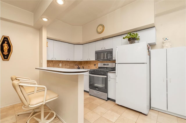 160-15 Powells Cove Blvd Unit D203, Beechhurst, NY 11357 - kitchen with freestanding refrigerator, gas range, black microwave, white cabinetry, and a peninsula
