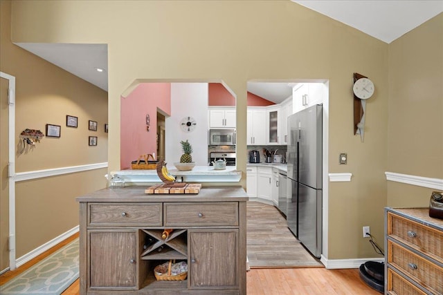 133-20 87th St Unit 3, Ozone Park, NY 11417 - kitchen with stainless steel appliances, light wood-style flooring, white cabinetry, baseboards, and vaulted ceiling
