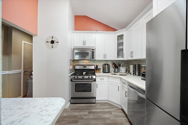 133-20 87th St Unit 3, Ozone Park, NY 11417 - kitchen with appliances with stainless steel finishes, a sink, vaulted ceiling, backsplash, and white cabinets