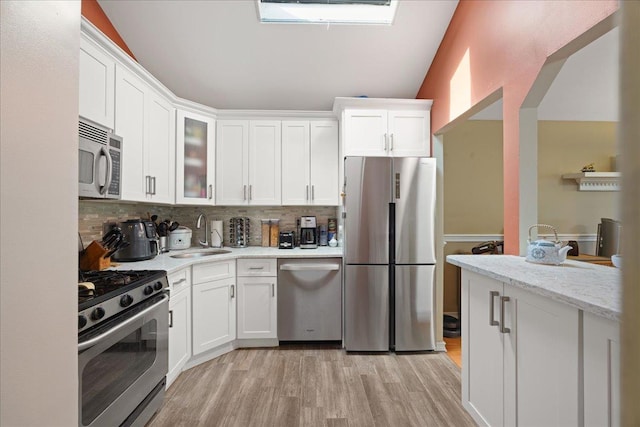 133-20 87th St Unit 3, Ozone Park, NY 11417 - kitchen featuring stainless steel appliances, a sink, light wood-style flooring, decorative backsplash, and white cabinetry