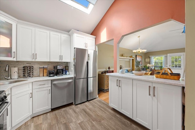 133-20 87th St Unit 3, Ozone Park, NY 11417 - kitchen with appliances with stainless steel finishes, a sink, backsplash, white cabinets, and a skylight
