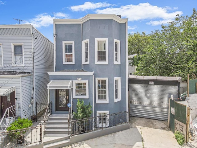 11-28 Welling Ct, Astoria, NY 11102 - view of front facade with stucco siding and a fenced front yard