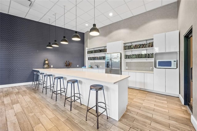 90 Bay Street Lndg Unit 6L, Staten Island, NY 10301 - kitchen featuring stainless steel refrigerator with ice dispenser, open shelves, white microwave, a breakfast bar, and wallpapered walls