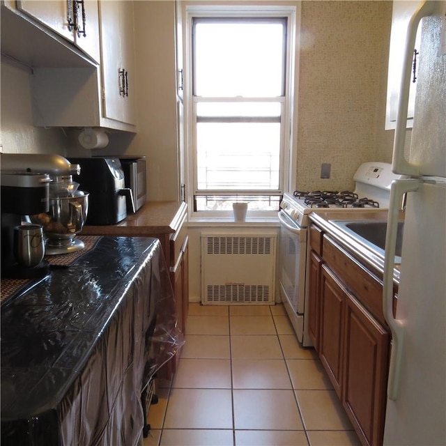 29 Abeel St Unit 6K, Yonkers, NY 10705 - kitchen with radiator heating unit, white appliances, light tile patterned flooring, and brown cabinetry