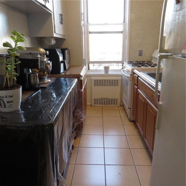 29 Abeel St Unit 6K, Yonkers, NY 10705 - kitchen featuring radiator heating unit, white appliances, light tile patterned flooring, and brown cabinetry