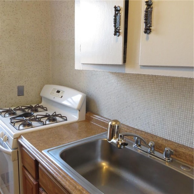29 Abeel St Unit 6K, Yonkers, NY 10705 - kitchen with white range with gas stovetop, decorative backsplash, a sink, and brown cabinets
