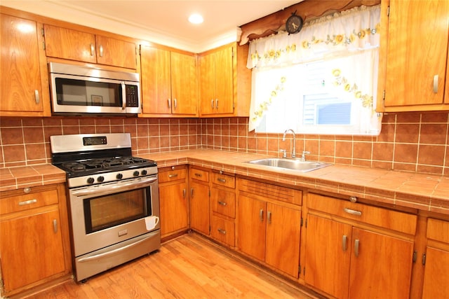 73-20 52nd Rd, Maspeth, NY 11378 - kitchen featuring appliances with stainless steel finishes, a sink, tile counters, light wood-style flooring, and backsplash