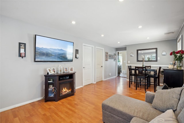 244 Laverne Ave, Holbrook, NY 11741 - living room with light wood-type flooring, a glass covered fireplace, recessed lighting, baseboards, and healthy amount of natural light