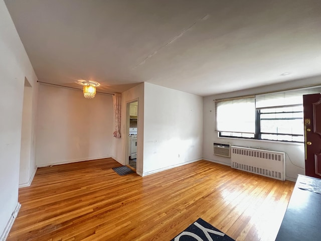 69-50 138th St Unit A, Flushing, NY 11367 - unfurnished room with radiator heating unit, light wood-style flooring, a wall unit AC, and baseboards