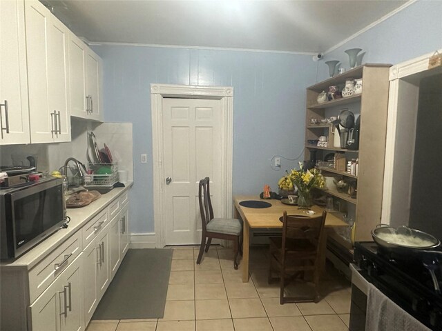 43 Oak St, Port Chester, NY 10573 - kitchen with stainless steel microwave, ornamental molding, white cabinetry, light tile patterned floors, and open shelves