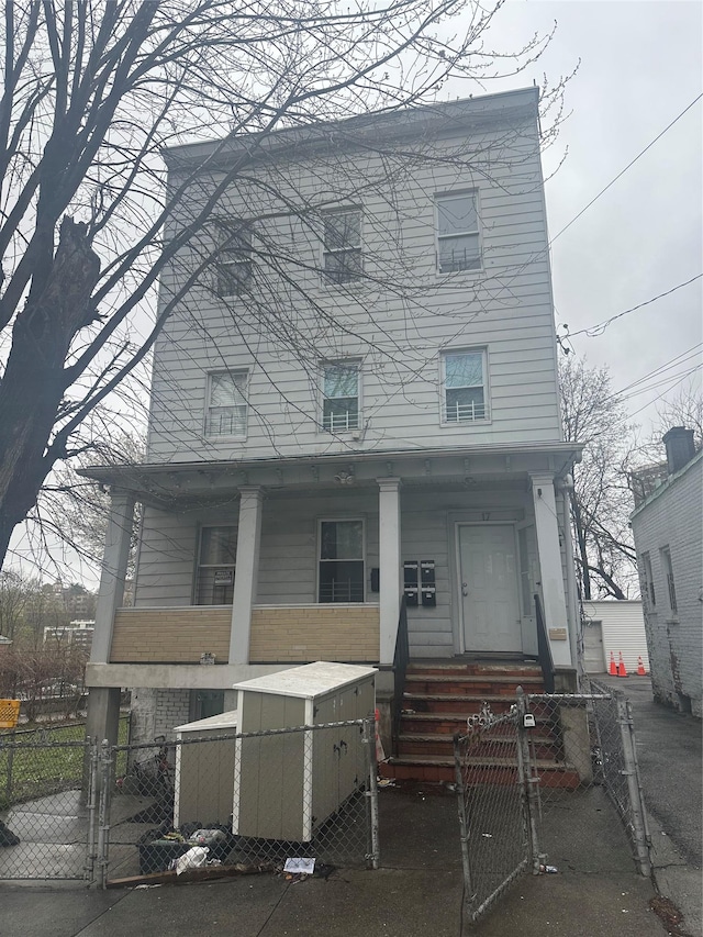 17 Chestnut St, Yonkers, NY 10701 - view of front of house with a gate, covered porch, a fenced front yard, and brick siding