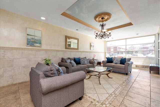 333 E Broadway Unit 1D, Long Beach, NY 11561 - living area featuring a tray ceiling, a textured ceiling, a wainscoted wall, a chandelier, and ornamental molding