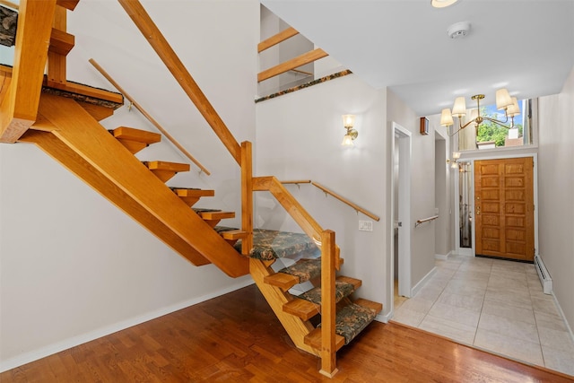 6 Chippewa Ct, Suffern, NY 10901 - staircase featuring a chandelier, baseboards, wood finished floors, and a baseboard radiator