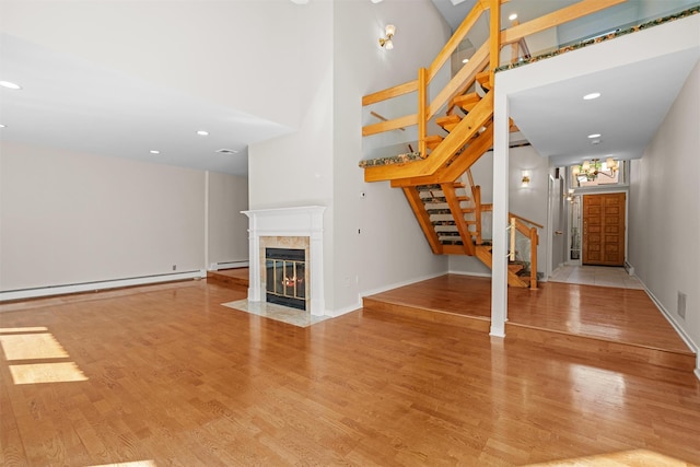 6 Chippewa Ct, Suffern, NY 10901 - unfurnished living room featuring stairs, a towering ceiling, wood finished floors, a high end fireplace, and a baseboard radiator