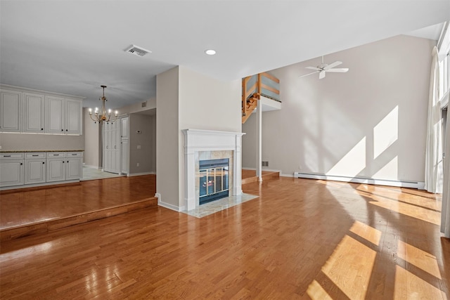 6 Chippewa Ct, Suffern, NY 10901 - unfurnished living room featuring a chandelier, a ceiling fan, light wood finished floors, baseboards, and a tiled fireplace