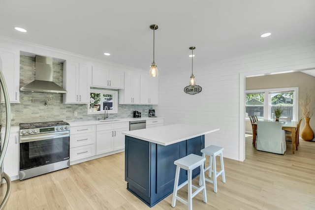 312 5th Ave, Greenport, NY 11944 - kitchen with wall chimney exhaust hood, stainless steel appliances, a sink, white cabinetry, and light countertops