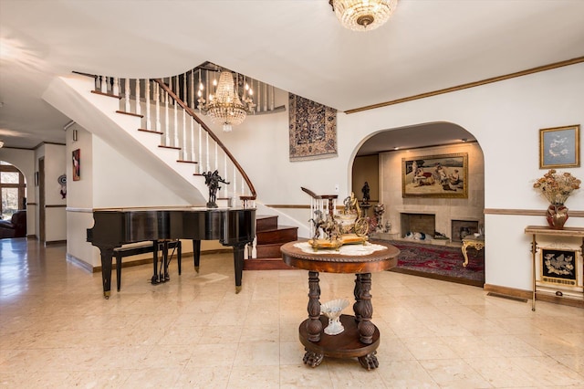 entryway featuring arched walkways, stairway, baseboards, a large fireplace, and ornamental molding