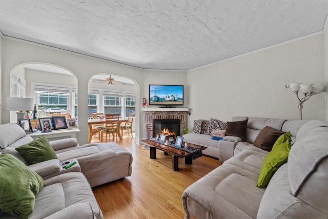 107 Underhill Ave, West Harrison, NY 10604 - living room featuring light wood-style floors, a textured ceiling, ornamental molding, a fireplace, and ceiling fan