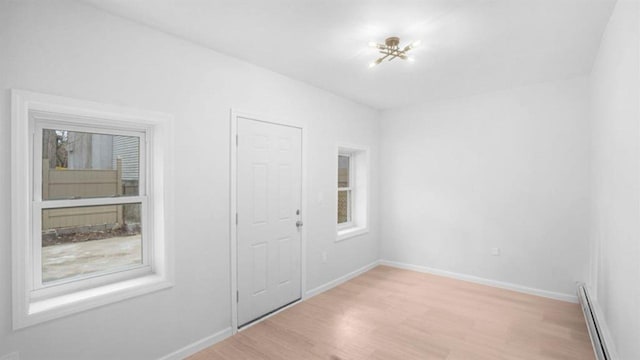 3412 Kingsland Ave, Bronx, NY 10469 - empty room with a baseboard heating unit, light wood-style flooring, and baseboards