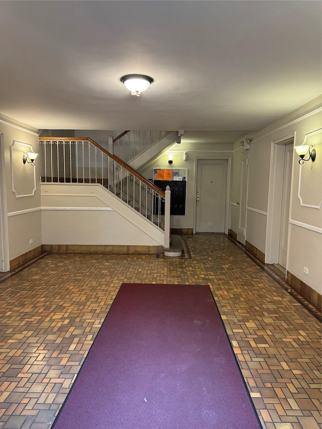 10 Welwyn Rd Unit 3E, Great Neck, NY 11021 - entrance foyer featuring brick patterned flooring, stairway, and baseboards