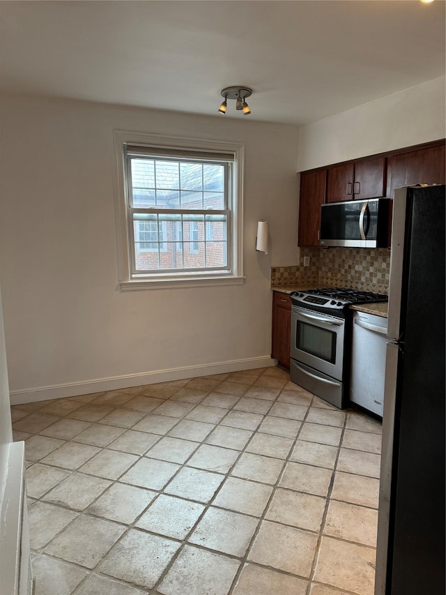 10 Welwyn Rd Unit 3E, Great Neck, NY 11021 - kitchen with stainless steel appliances, decorative backsplash, baseboards, light countertops, and dark brown cabinets