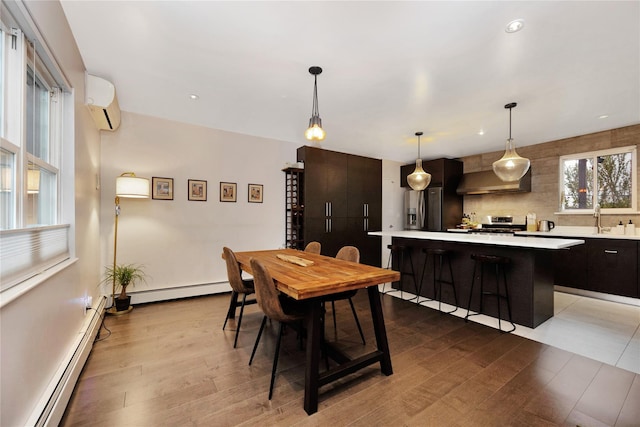 13915 Coolidge Ave, Briarwood, NY 11435 - dining room featuring baseboard heating, light wood-style floors, a wall mounted air conditioner, and recessed lighting