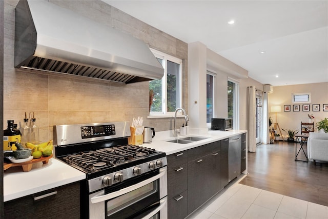 13915 Coolidge Ave, Briarwood, NY 11435 - kitchen with stainless steel appliances, wall chimney range hood, a sink, decorative backsplash, and light countertops
