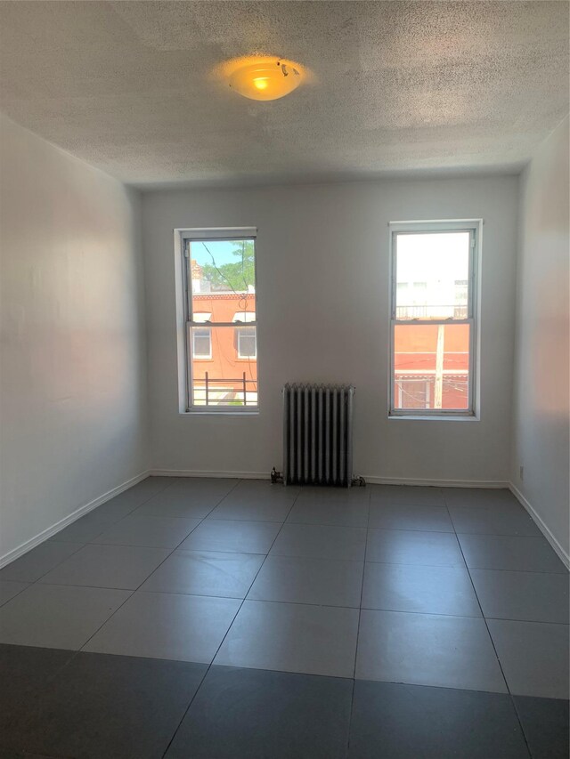 199 Lincoln Ave, Brooklyn, NY 11208 - unfurnished room with radiator heating unit, plenty of natural light, tile patterned flooring, and a textured ceiling