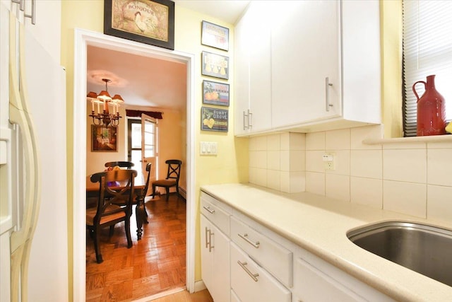 40 Stoner Ave Unit 1-I, Great Neck, NY 11021 - kitchen featuring a chandelier, light countertops, white cabinetry, freestanding refrigerator, and tasteful backsplash