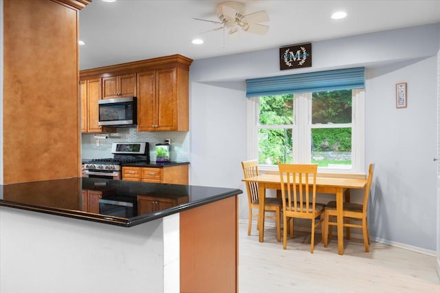 71 Harlan Dr, New Rochelle, NY 10804 - kitchen with appliances with stainless steel finishes, dark countertops, decorative backsplash, light wood-style flooring, and brown cabinets