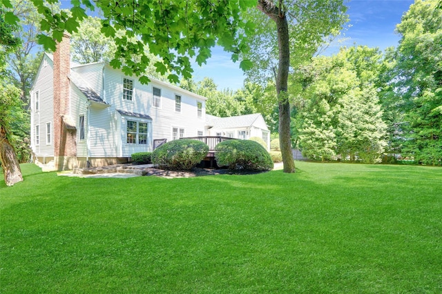 14 Wainscott Ln, East Setauket, NY 11733 - back of property featuring a chimney, a yard, and a wooden deck