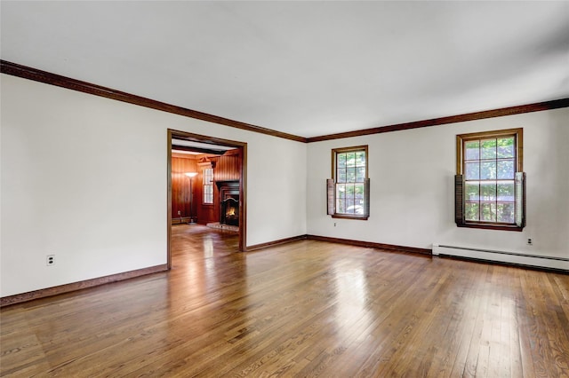 14 Wainscott Ln, East Setauket, NY 11733 - empty room featuring plenty of natural light, hardwood / wood-style flooring, a baseboard heating unit, baseboards, and crown molding