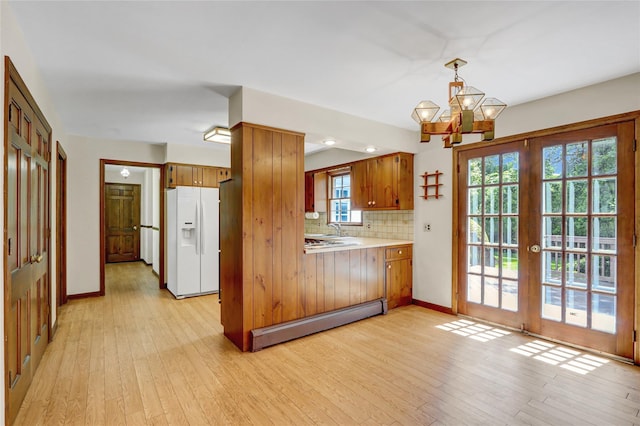 14 Wainscott Ln, East Setauket, NY 11733 - kitchen with white refrigerator with ice dispenser, a baseboard heating unit, light wood finished floors, a sink, and backsplash