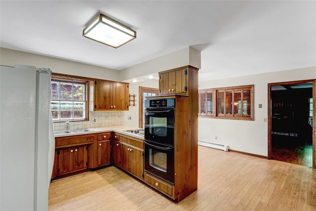 14 Wainscott Ln, East Setauket, NY 11733 - kitchen with a baseboard heating unit, white appliances, a sink, light countertops, and light wood finished floors