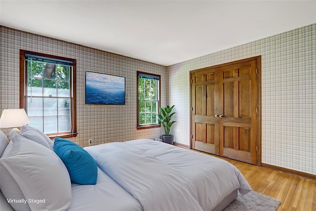 14 Wainscott Ln, East Setauket, NY 11733 - bedroom with wallpapered walls, light wood-style flooring, and baseboards