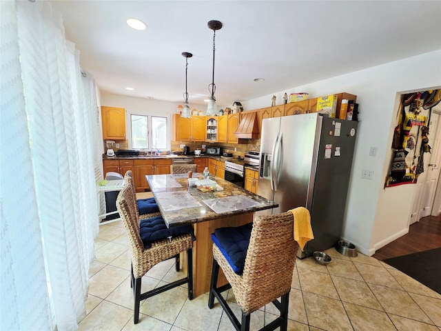 81 Anchor St, Riverhead, NY 11901 - kitchen with appliances with stainless steel finishes, a sink, a kitchen island, a breakfast bar, and light tile patterned flooring