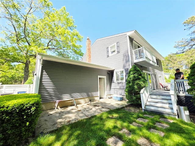 81 Anchor St, Riverhead, NY 11901 - rear view of house with a balcony, a chimney, and a patio area