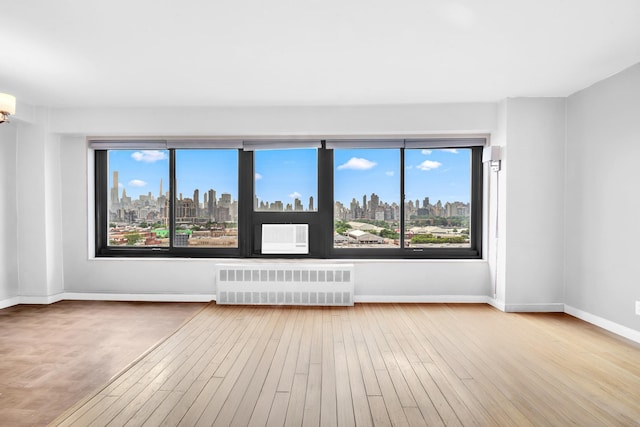3343 14th St Unit 12B, Astoria, NY 11106 - spare room with radiator, a skyline view, hardwood / wood-style flooring, and plenty of natural light