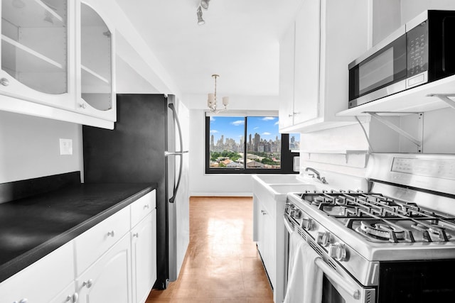 3343 14th St Unit 12B, Astoria, NY 11106 - kitchen featuring stainless steel appliances, a sink, white cabinets, glass insert cabinets, and a chandelier