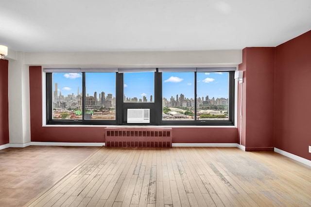 3343 14th St Unit 12B, Astoria, NY 11106 - spare room with radiator heating unit, a skyline view, hardwood / wood-style floors, and baseboards