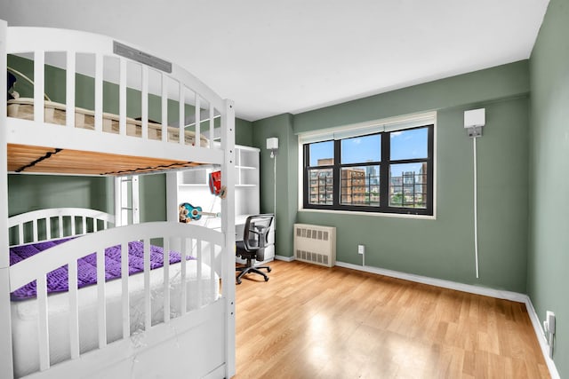 3343 14th St Unit 12B, Astoria, NY 11106 - bedroom with radiator heating unit, wood finished floors, baseboards, and an office area
